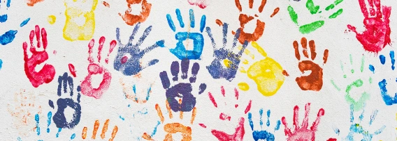 Different color handprints on a white wall.