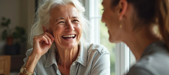 Two women sharing a warm conversation over coffee, one laughing genuinely.