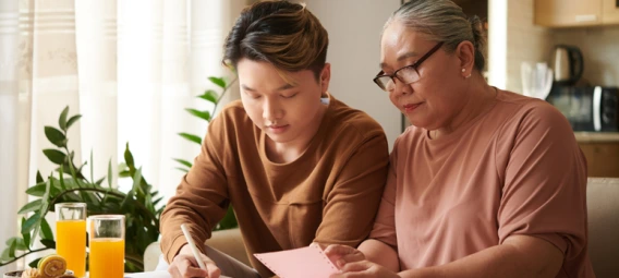 Young man reviewing paperwork with an older woman at a kitchen table
