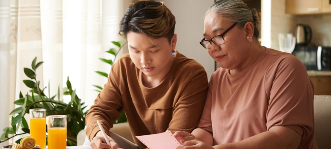 Young man reviewing paperwork with an older woman at a kitchen table