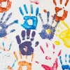 Different color handprints on a white wall.