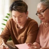 Young man reviewing paperwork with an older woman at a kitchen table